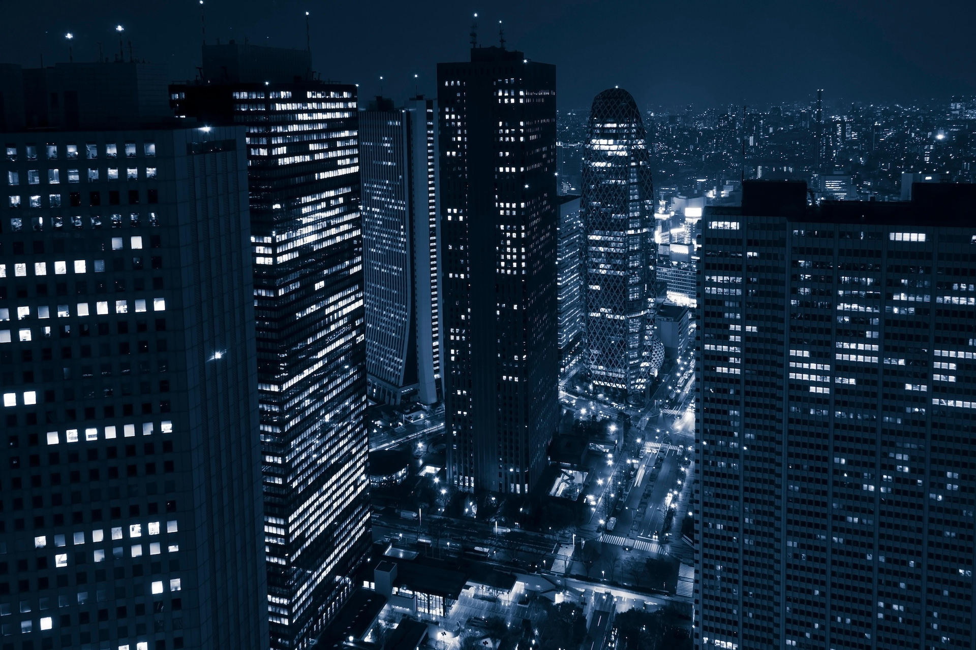 Office towers at night seen from above, their windows lit, with lit streets below