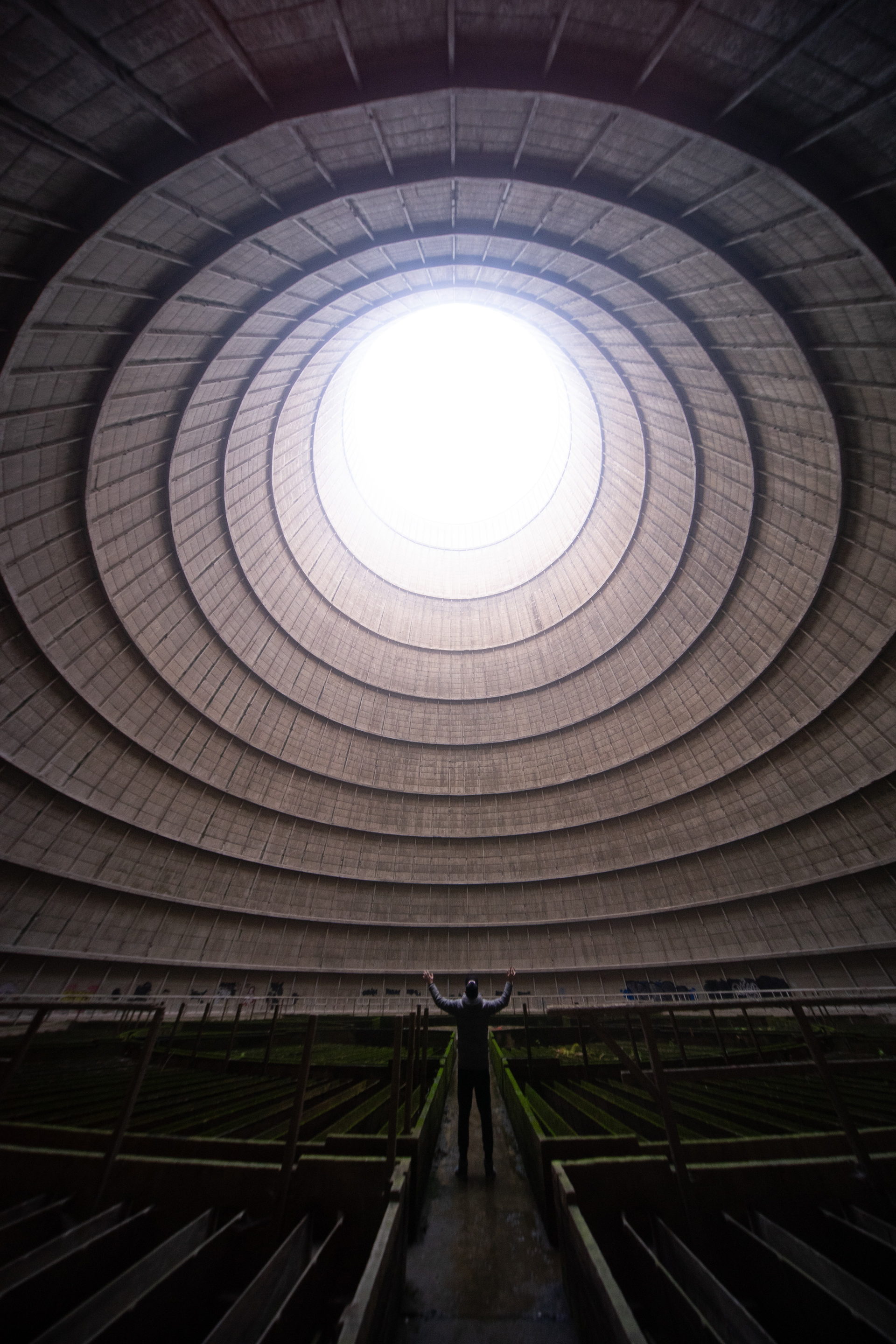 A vast circular tower interior, open to the sky through a round opening at the top