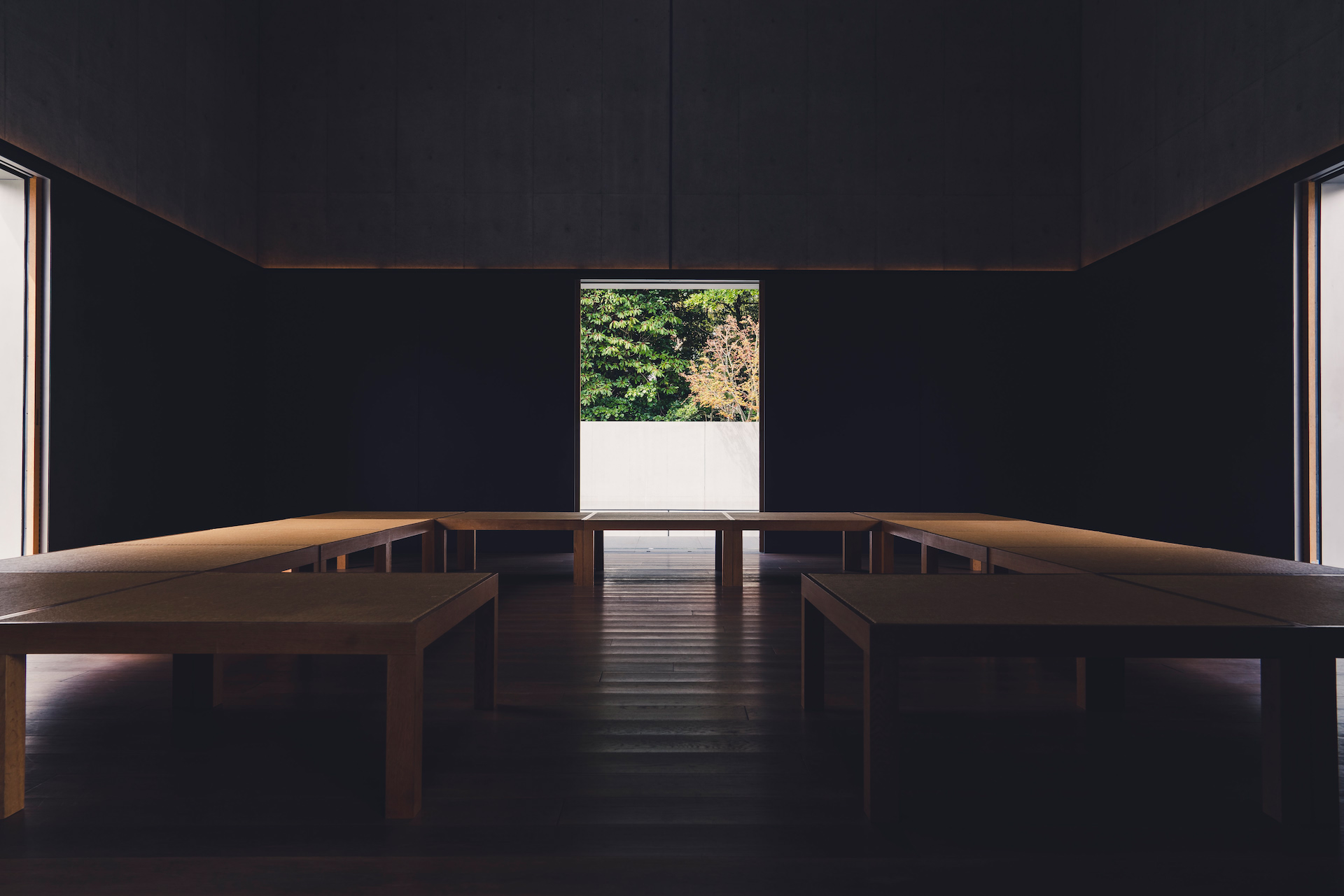 A dark, quiet room with a long table and a bright window at the far end