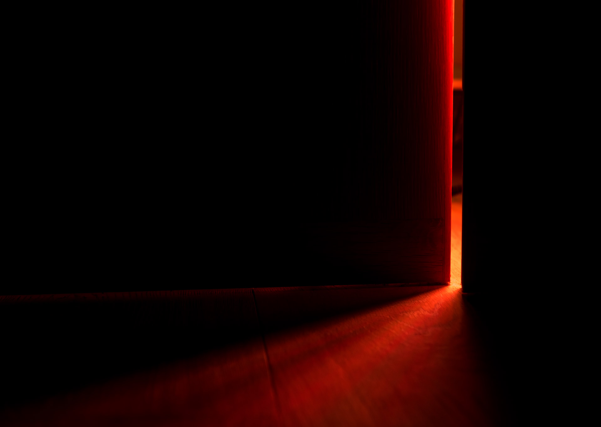 Red light falling through an open door into a dark room