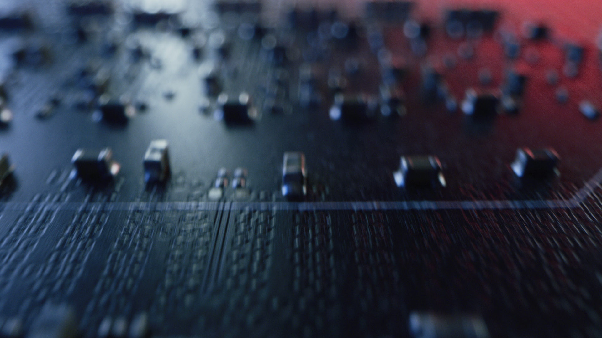 A printed circuit board in close-up, its components lit blue and red