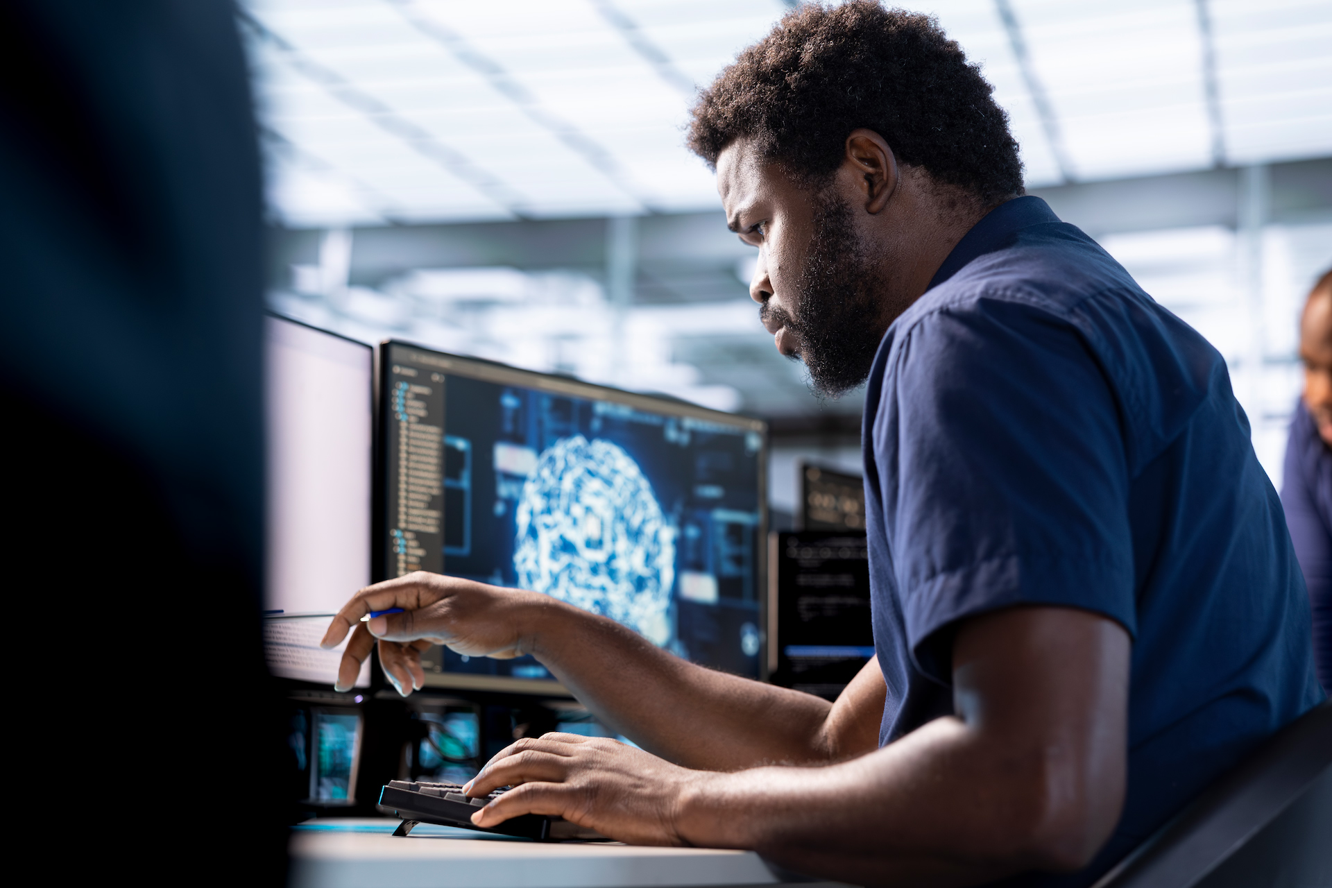 An engineer at a workstation in a data centre, a neural-network visual on screen