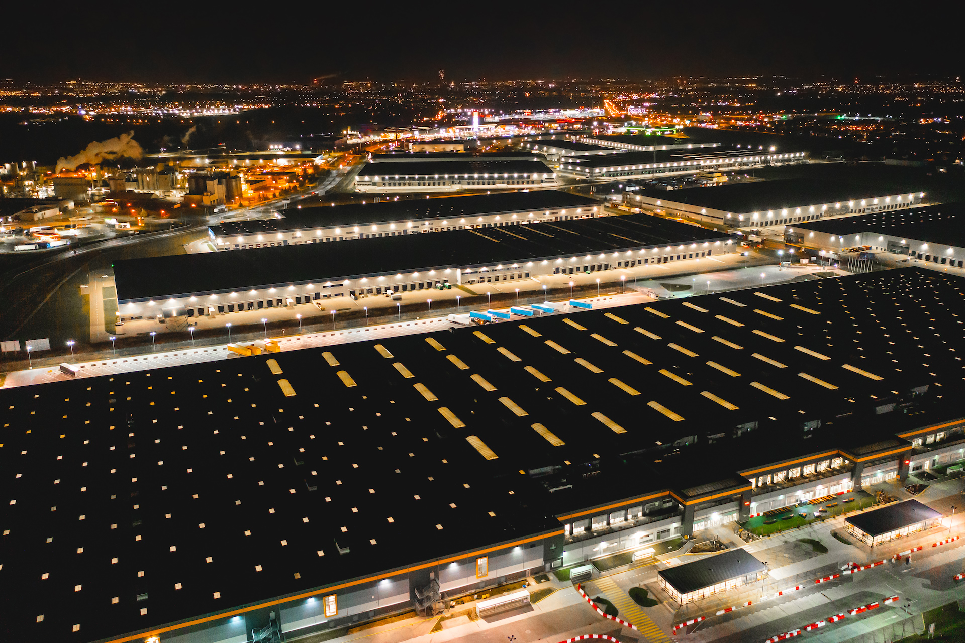 A logistics park at night from the air, its loading docks and trucks lit